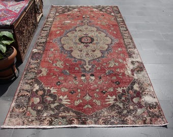 May include: A vintage red and brown rug with a floral pattern. The rug has a faded, distressed look and is made of wool.