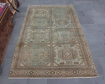 May include: A beige and brown patterned rug with a geometric design. The rug has a light green and brown color scheme and a border of brown and beige.