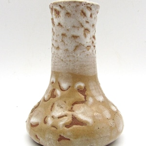 May include: A small, brown ceramic vase with a white glaze and a textured surface. The vase has a wide base and a narrow neck.