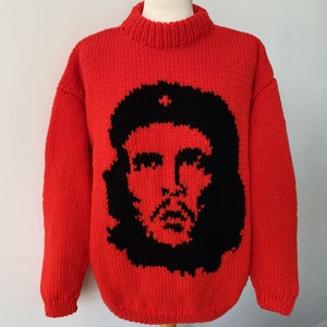 以下が含まれることがあります： 赤いニットセーターに、チェ・ゲバラの白黒の画像が前面にプリントされています。