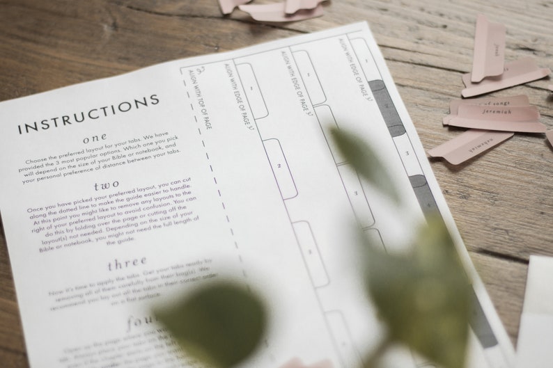 Op de afbeelding: Instructies voor het maken van tabs voor een Bijbel of notitieboek. De instructies omvatten het uitlijnen van de tabs met de rand van de pagina en de bovenkant van de pagina. De afbeelding toont een wit vel papier met zwarte tekst en lijnen.