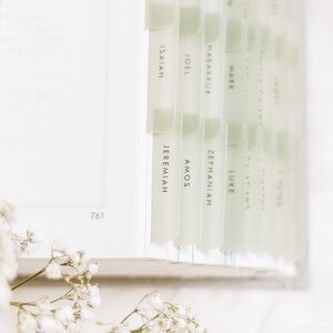 Op de afbeelding: Een close-up van een wit boek met groene tabs met de namen van boeken uit de Bijbel, waaronder Jesaja, Jeremia, Amos, Zefanja, Jo&euml;l, Habakuk, Markus, Lucas en anderen.