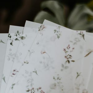 Puede incluir: Un conjunto de cuatro hojas de papel blancas, transl&uacute;cidas, con estampado floral y agujeros perforados en el borde izquierdo. Las hojas son ligeramente transl&uacute;cidas y tienen un delicado dise&ntilde;o floral en tonos verdes y rosas.