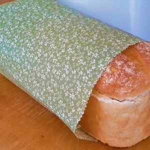 May include: A loaf of white bread wrapped in green fabric with a white floral pattern.
