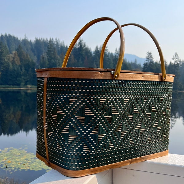 Picnic basket with basket weave pattern. Hinged oblong basket with swing handles, pressboard lid. Dark green diamond weave includes insert