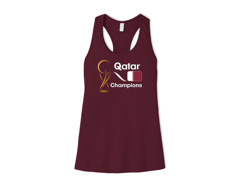 May include: A maroon tank top with a white graphic of a trophy, the word "Qatar", a stylized wave, and the flag of Qatar. The text "Champions" is below the graphic.