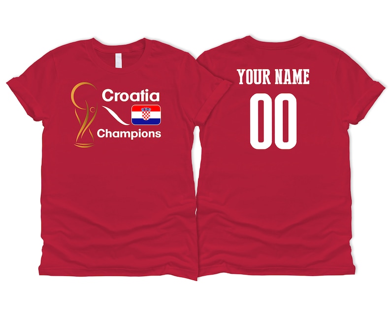 Puede incluir: Camiseta roja con un trofeo dorado, la palabra "Croacia", la bandera croata y la palabra "Campeones". La parte posterior de la camiseta tiene las palabras "Tu nombre" y el n&uacute;mero "00" en blanco.