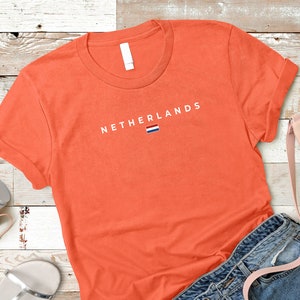 May include: Orange t-shirt with the text "NETHERLANDS" and the Dutch flag printed on the front.
