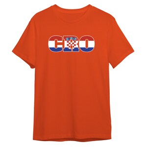 Puede incluir: Camiseta naranja con la palabra "CRO" en letras azules con la bandera croata dentro de cada letra.