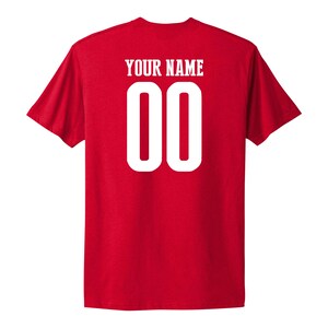 May include: Red t-shirt with white text that says "YOUR NAME" and the number "00" on the back.