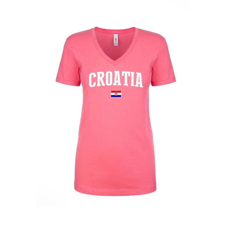 May include: A pink v-neck t-shirt with the word "CROATIA" printed in white on the front. A small Croatian flag is printed below the word.