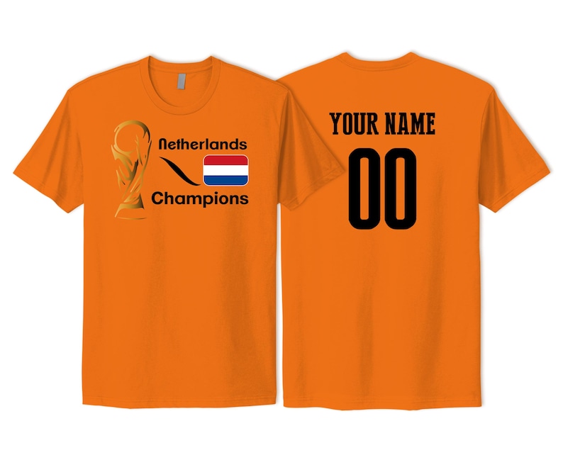 May include: An orange short-sleeved t-shirt featuring a gold trophy graphic, the text Netherlands Champions, and a Dutch flag on the front. The back displays the text YOUR NAME above the black numbers 00 in a bold, block-style font.