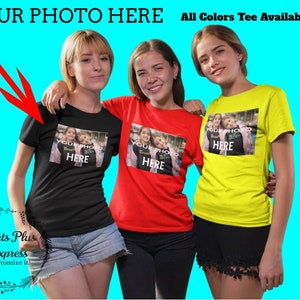 May include: Three women wearing t-shirts with a photo upload area. The text "YOUR PHOTO HERE" is printed on each shirt. The shirts are black, red, and yellow. The text "All Colors Tee Available" is printed at the top of the image.