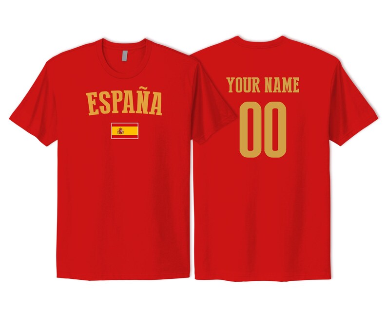 May include: A red short-sleeved t-shirt showing front and back views. The front features the text ESPA&Ntilde;A in gold above a small Spanish flag. The back displays the text YOUR NAME in gold above the gold numbers 00, centered on the red fabric.