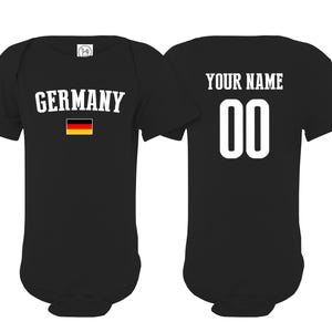 May include: A black short-sleeved baby bodysuit featuring the word GERMANY in white text above a small German flag on the front, and the text YOUR NAME above the number 00 in white on the back, showcasing both sides of the garment.