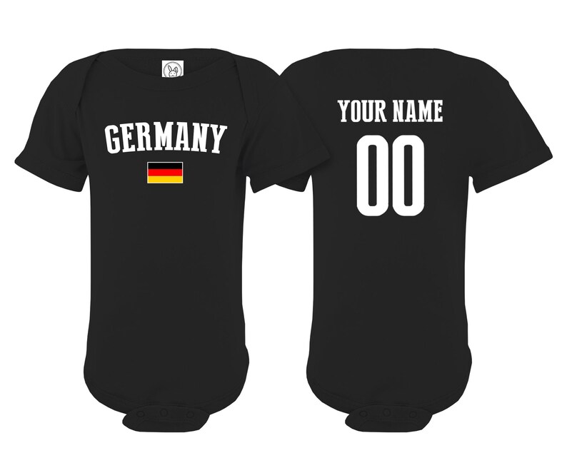 May include: A black short-sleeved baby bodysuit featuring the word GERMANY in white text above a small German flag on the front, and the text YOUR NAME above the number 00 in white on the back, showcasing both sides of the garment.
