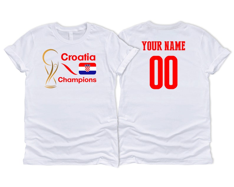 Puede incluir: Dos camisetas blancas, una con un trofeo dorado, el texto "Croatia Champions" y la bandera croata, y la otra con el texto "YOUR NAME" y el n&uacute;mero "00" en rojo.