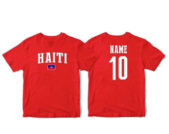 May include: Two red t-shirts, one with the word "HAITI" and the Haitian flag, the other with the word "NAME" and the number "10" in white.