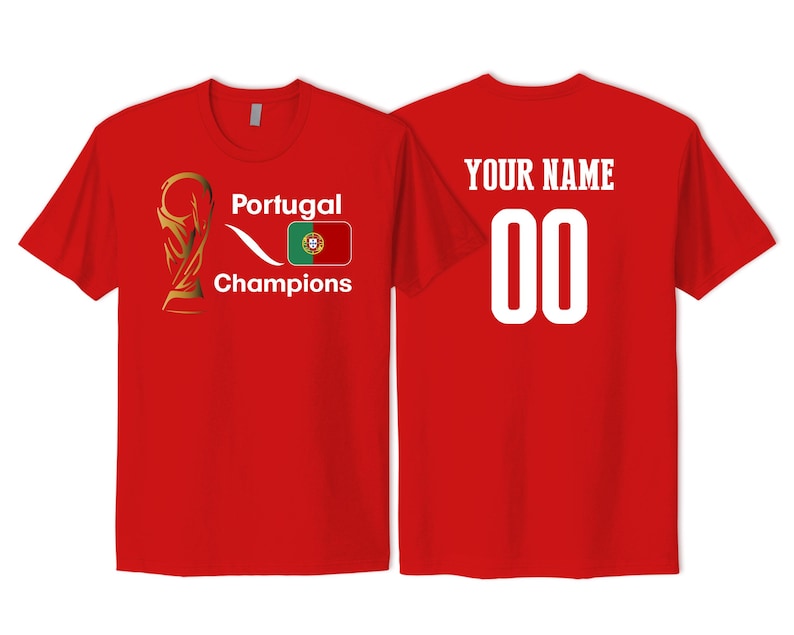 May include: A red short-sleeved t-shirt featuring a gold trophy graphic, the text Portugal Champions, and the Portugal flag on the front. The back displays the text YOUR NAME above the number 00 in large white font on the same red fabric.