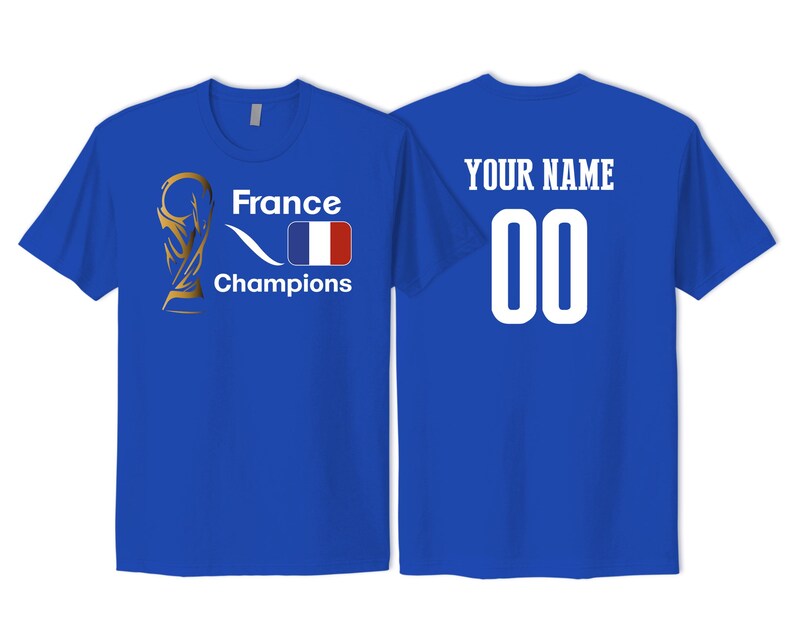 May include: A royal blue t-shirt featuring a gold trophy graphic, the text France Champions, and a French flag on the front. The back displays the text YOUR NAME above the number 00 in white lettering. The shirt has short sleeves and a crew neck.