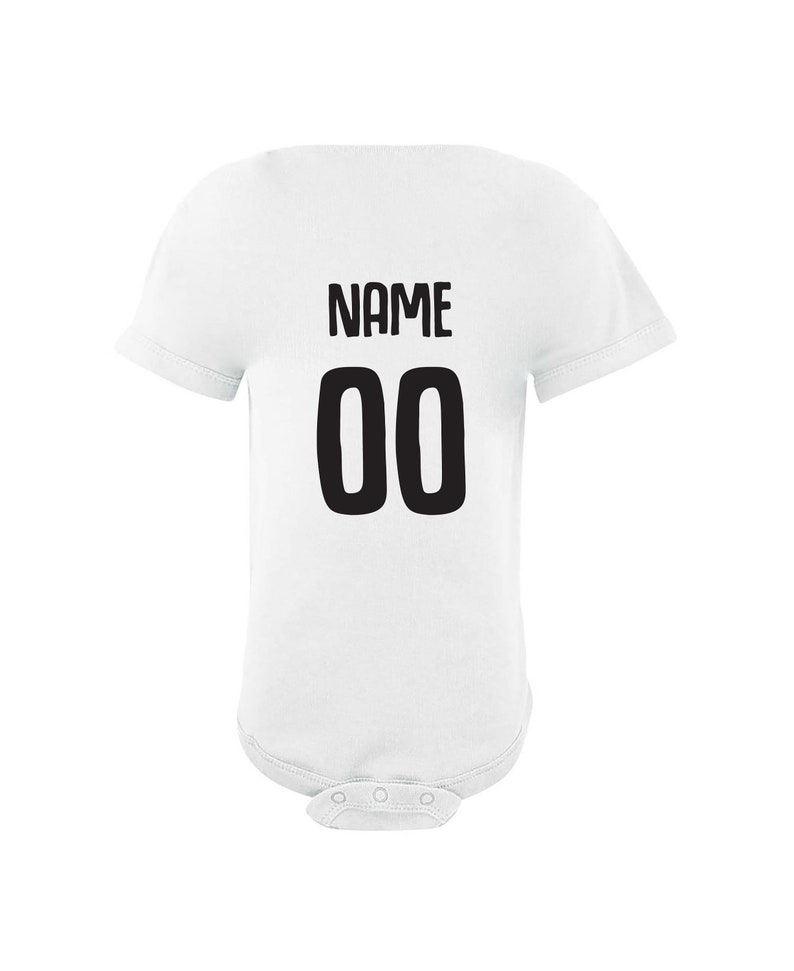 May include: White baby bodysuit with black text that says "NAME 00" on the back.