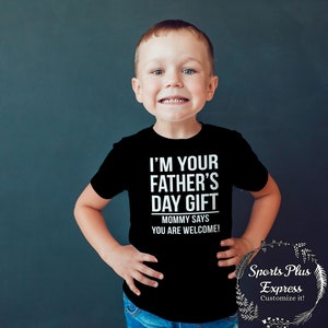 May include: A young child wearing a black t-shirt with the text "I'm your father's day gift. Mommy says you are welcome!" in white lettering.
