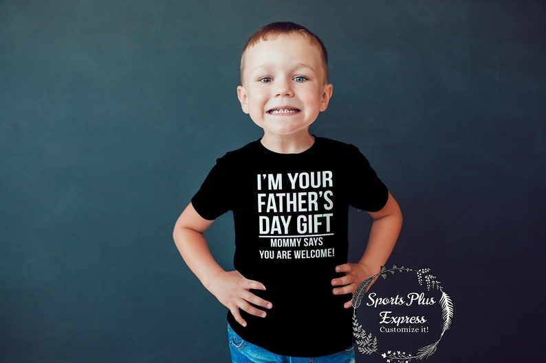 May include: A young child wearing a black t-shirt with the text "I'm your father's day gift. Mommy says you are welcome!" in white lettering.