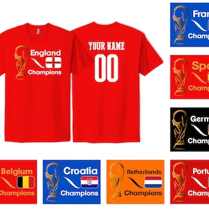 May include: A red t-shirt featuring a gold trophy graphic, the text England Champions, and the England flag on the front. The back displays the text YOUR NAME and the number 00 in white. Additional color variations for other countries are shown.