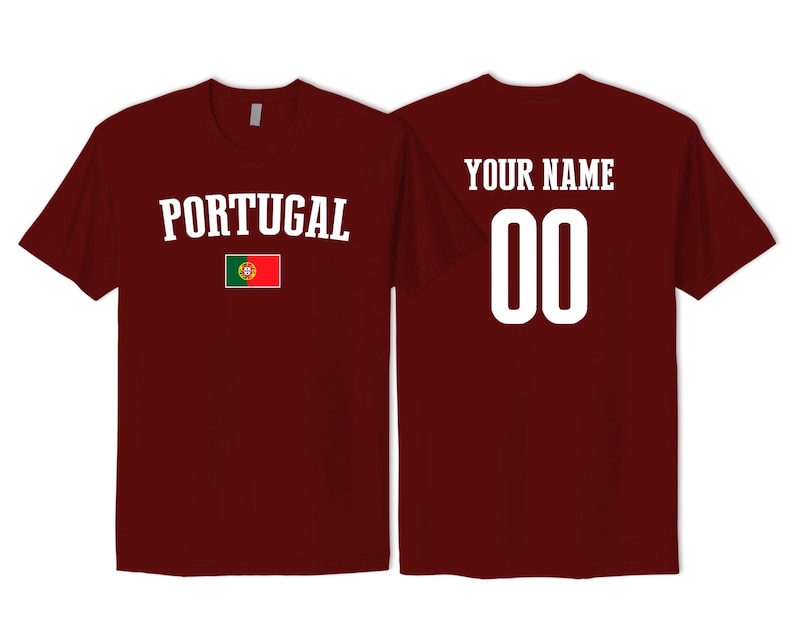 May include: A maroon short-sleeved t-shirt featuring the word PORTUGAL in white text above the Portugal national flag on the front, and the text YOUR NAME above the number 00 in white on the back of the garment.
