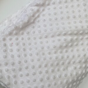 May include: White plush fabric with a textured dot pattern. The fabric is soft and has a subtle sheen.