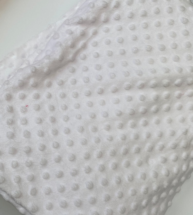 May include: White plush fabric with a textured dot pattern. The fabric is soft and has a subtle sheen.