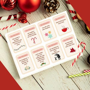 May include: A set of 8 pink and white affirmation cards with a festive winter theme. Each card features a different affirmation related to love, joy, gratitude, and abundance. The cards are decorated with snowflakes, candy canes, and other wintery imagery.