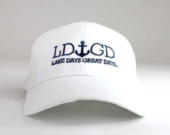 May include: White baseball cap with a navy blue embroidered anchor and the text "LDGD LAKE DAYS GREAT DAYS..."