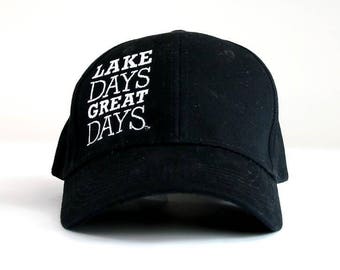 May include: Black baseball cap with white embroidered text that reads "LAKE DAYS GREAT DAYS".
