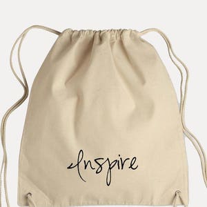 May include: A beige drawstring bag with the word "inspire" written in black cursive on the front.