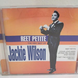 May include: CD case featuring Jackie Wilson's album "Reet Petite: The Very Best Of." The cover has an orange and white background with the singer in a black suit. The album title and song titles are also visible.
