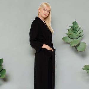 May include: A black waffle weave robe with a shawl collar and a tie belt. The robe has two pockets on the front.