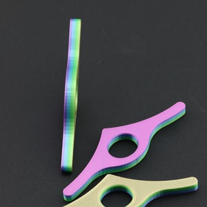May include: Three colorful book page holders in shades of purple, green, and yellow. One is standing upright, while the other two are lying flat. Each has a circular opening and a layered design, perfect for keeping your place in a book.
