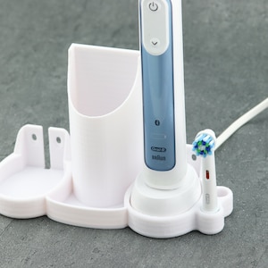 Puede incluir: Soporte de carga blanco para cepillo de dientes eléctrico con un cepillo de dientes Oral-B azul y dos cabezales de cepillo.