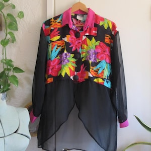 May include: A vintage button-down shirt with a vibrant floral print in red, pink, yellow, and blue on a black background. The shirt features a pink collar and cuffs, with sheer black sleeves and a split hem.