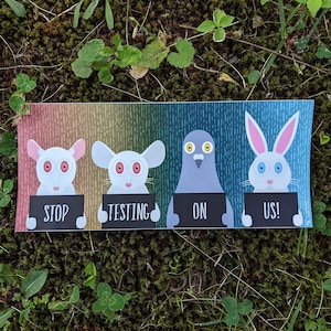 May include: A sticker with a rainbow background featuring four animals holding signs that say "Stop", "Testing", "On", and "Us!" The animals are a white mouse, a white mouse, a gray pigeon, and a white rabbit.