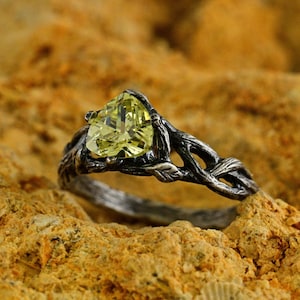 Puede incluir: Un anillo de plata con una piedra preciosa verde engastada en un dise&ntilde;o de rama.