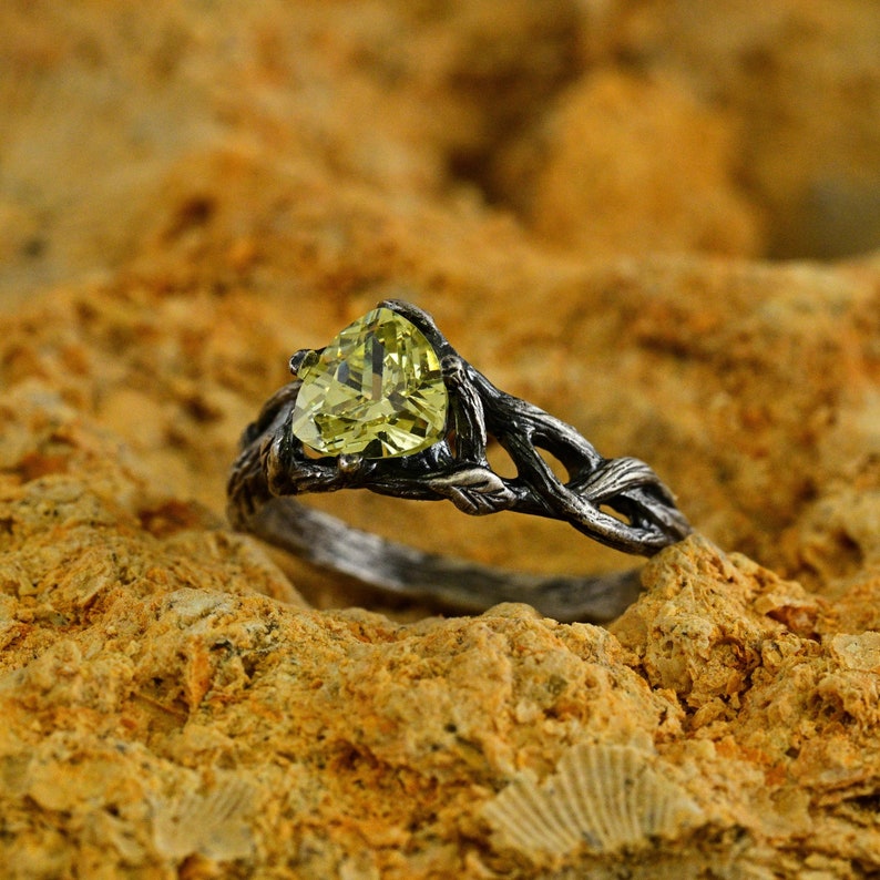 Puede incluir: Un anillo de plata con una piedra preciosa verde engastada en un dise&ntilde;o de rama.