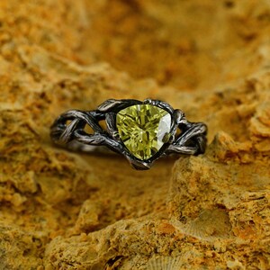 Puede incluir: Un anillo de plata con una piedra preciosa verde engastada en un dise&ntilde;o de rama retorcida.