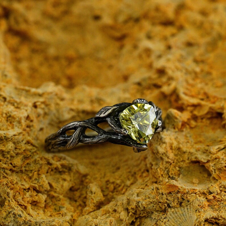 Puede incluir: Un anillo de plata con una piedra preciosa verde engastada en un dise&ntilde;o de rama retorcida.