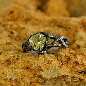 Puede incluir: Un anillo de plata con un dise&ntilde;o de rama retorcida y una gran piedra preciosa amarilla facetada.