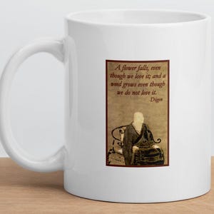 May include: White ceramic mug with a quote by Dogen: "A flower falls, even though we love it; and a weed grows even though we do not love it." The quote is printed in brown text on a beige background with an illustration of a person sitting in a chair.