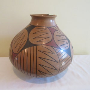 May include: A brown ceramic vase with a geometric pattern of black, brown, and red lines and shapes.