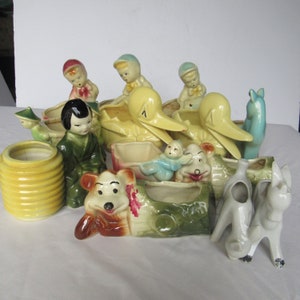 May include: A collection of vintage ceramic planter figurines, including a duck, a bird, a dog, a bear, and a girl. The figurines are painted in various colors, including yellow, blue, green, and red.