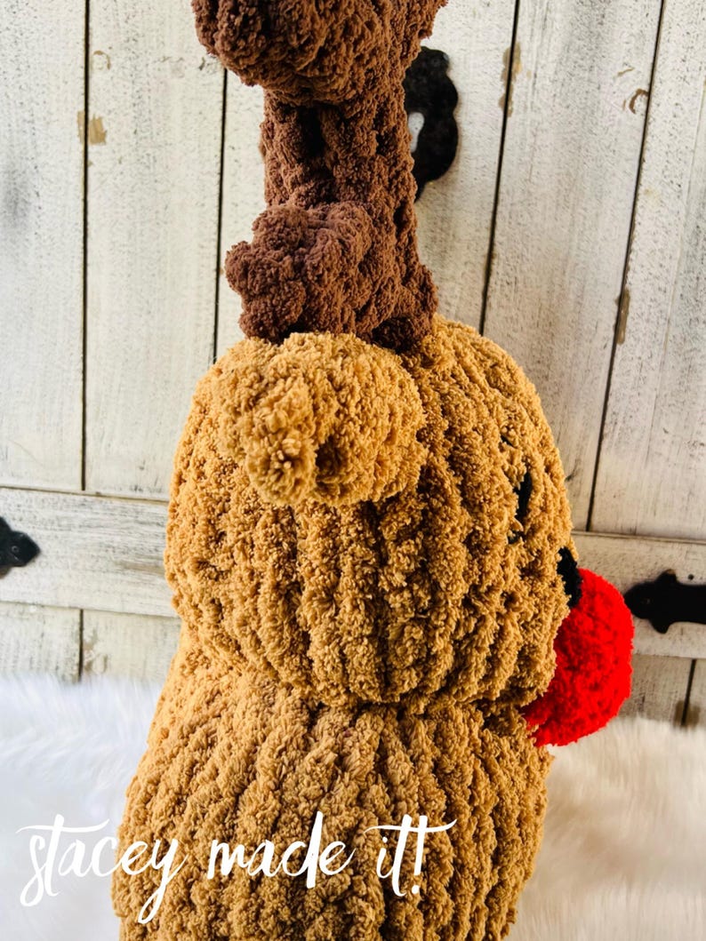 May include: A handmade, plush reindeer head in shades of brown with a red nose. The reindeer has large, textured antlers and a fluffy body. The text "stacey made it!" is visible at the bottom of the image.